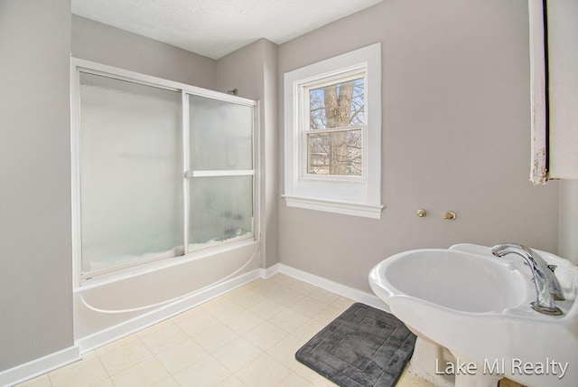 bathroom with bath / shower combo with glass door, sink, and a textured ceiling