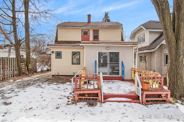 snow covered rear of property with a wooden deck