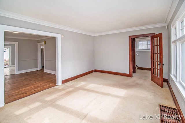 unfurnished room with crown molding, light carpet, and french doors