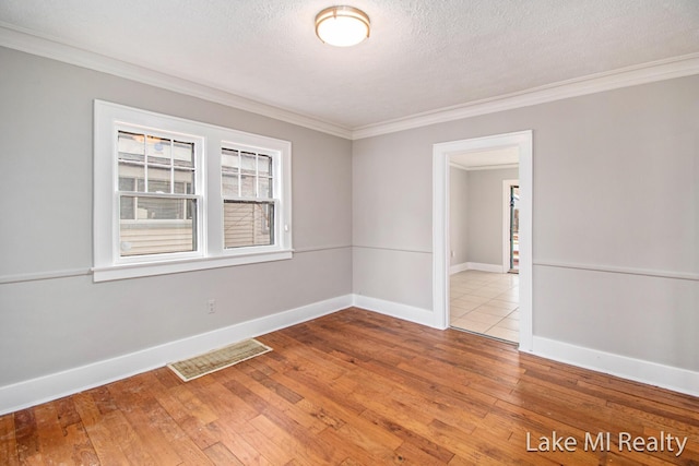 unfurnished room featuring crown molding, light hardwood / wood-style floors, and a textured ceiling