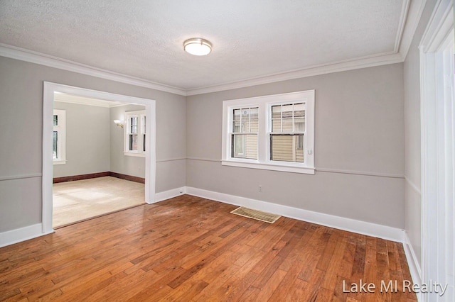 unfurnished room with hardwood / wood-style flooring, ornamental molding, and a textured ceiling