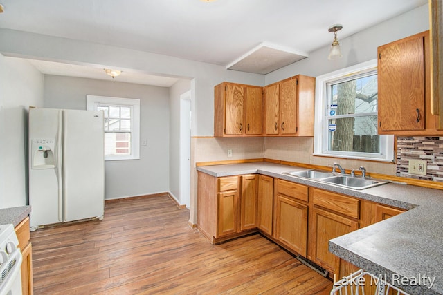 kitchen with sink, white appliances, decorative backsplash, and light wood-type flooring