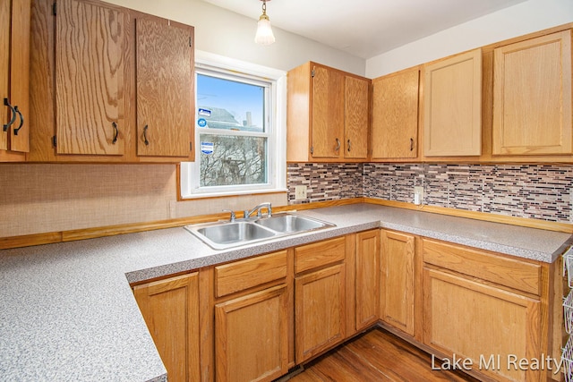 kitchen with dark wood-type flooring, hanging light fixtures, sink, and decorative backsplash