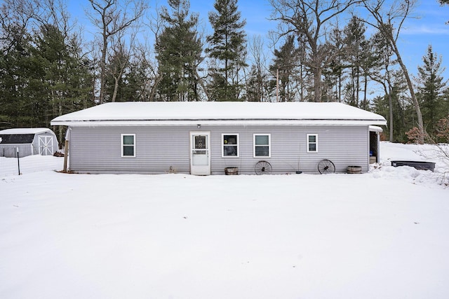 snow covered rear of property with a storage unit