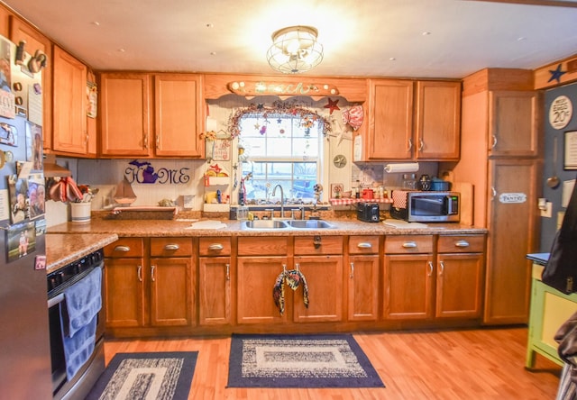 kitchen featuring stainless steel appliances, sink, light stone counters, and light hardwood / wood-style floors