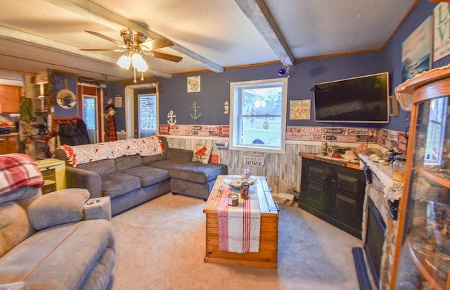 carpeted living room with wooden walls, ceiling fan, and beam ceiling