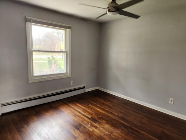 spare room with dark wood-type flooring, ceiling fan, and a baseboard heating unit