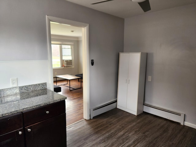 kitchen with dark brown cabinetry, dark hardwood / wood-style flooring, light stone counters, and baseboard heating