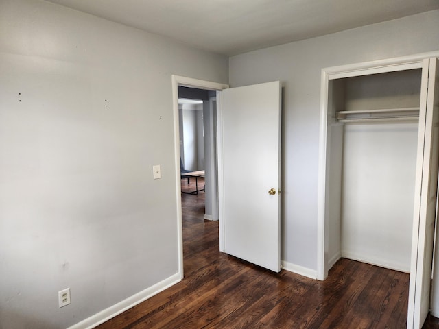 unfurnished bedroom featuring dark hardwood / wood-style flooring and a closet