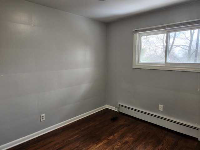 spare room with dark wood-type flooring and a baseboard radiator