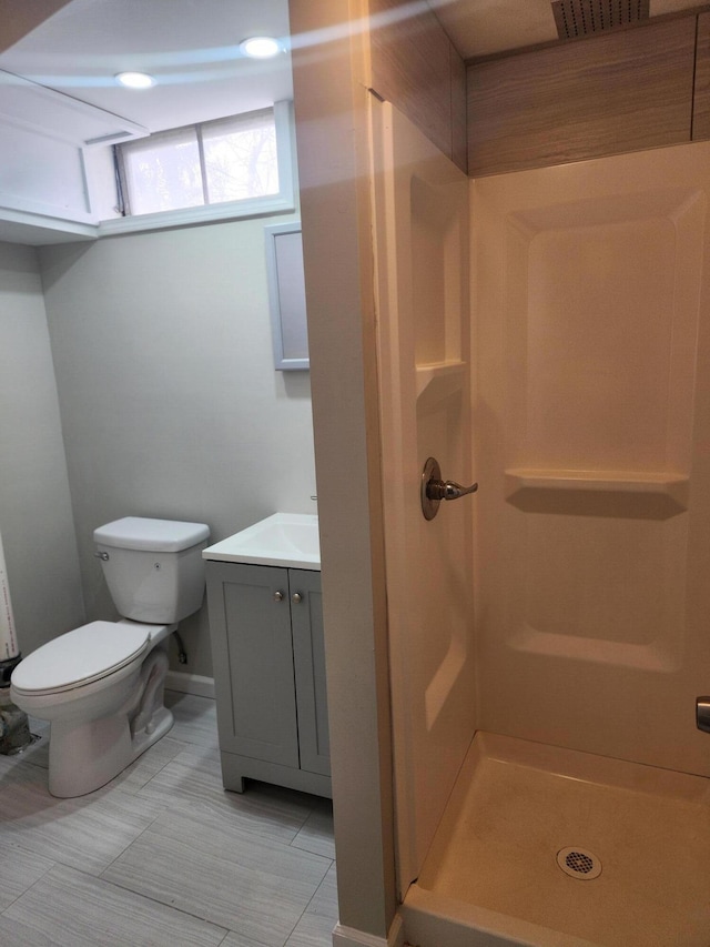 bathroom with walk in shower, vanity, and toilet