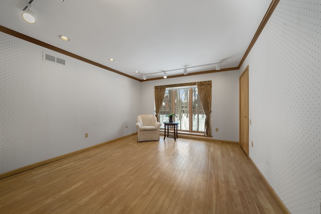 unfurnished room with crown molding, wallpapered walls, rail lighting, and visible vents