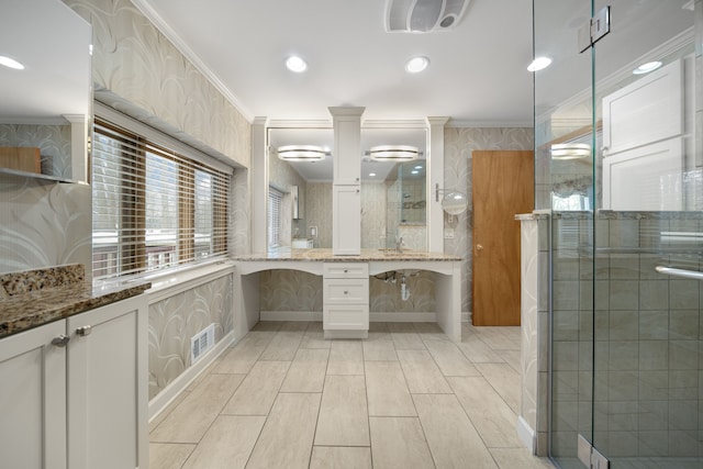 bathroom with vanity, ornamental molding, a shower stall, and wallpapered walls