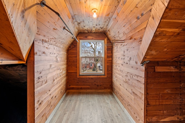 additional living space with lofted ceiling, wooden ceiling, light wood-type flooring, and wood walls