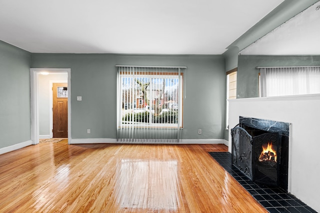 unfurnished living room with a tiled fireplace and hardwood / wood-style floors