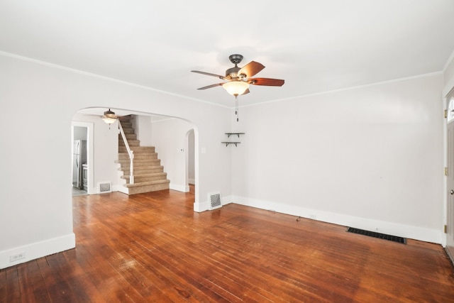 unfurnished room featuring arched walkways, wood finished floors, visible vents, and a ceiling fan