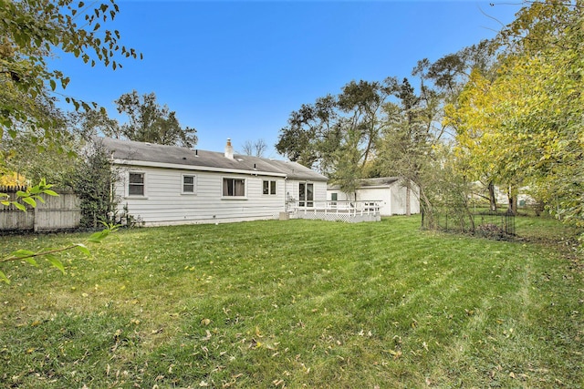 rear view of house featuring a yard and a deck