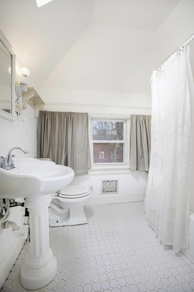 bathroom with vaulted ceiling, shower / bathtub combination with curtain, and toilet