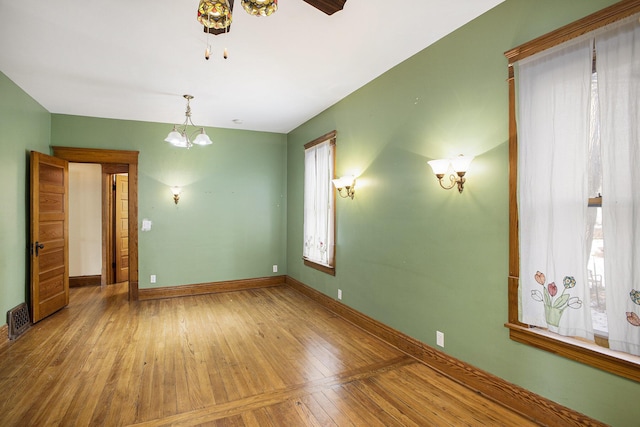 unfurnished room featuring hardwood / wood-style floors and a notable chandelier