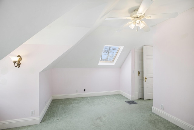 bonus room featuring vaulted ceiling with skylight, light colored carpet, and ceiling fan