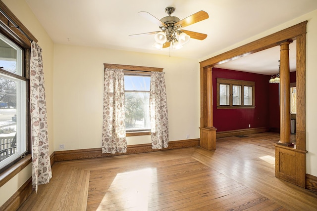 unfurnished room featuring hardwood / wood-style floors, ceiling fan, and ornate columns