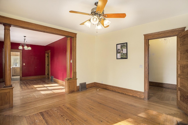 unfurnished room with hardwood / wood-style floors, ceiling fan with notable chandelier, and decorative columns