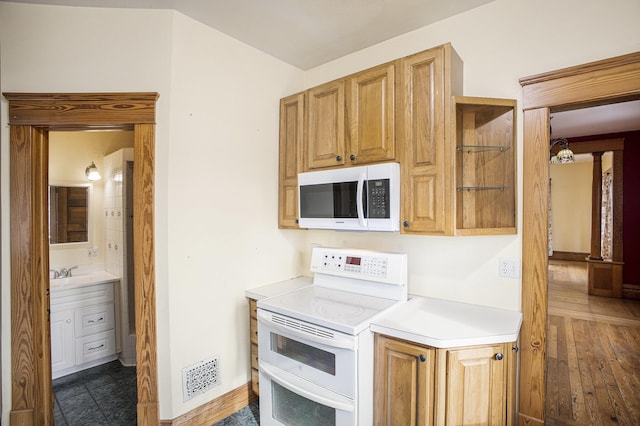 kitchen featuring dark wood-type flooring, white appliances, and sink