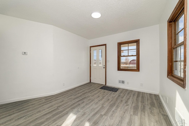 spare room with light hardwood / wood-style floors and a textured ceiling