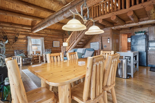 dining room featuring log walls, beam ceiling, light hardwood / wood-style floors, and wooden ceiling