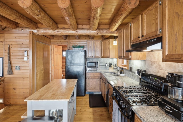 kitchen featuring wooden walls, butcher block counters, sink, and black appliances