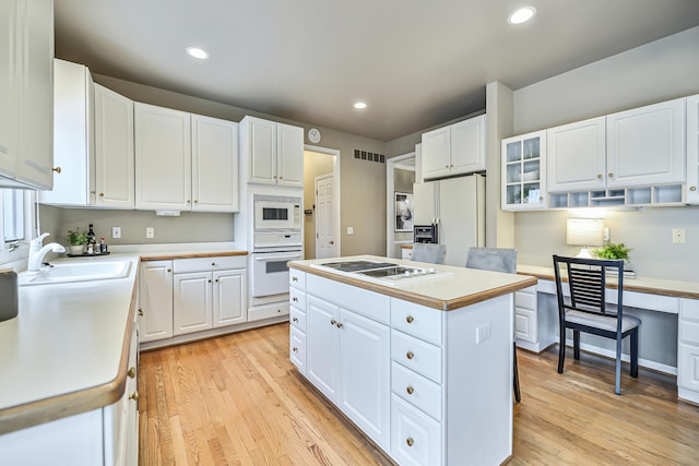 kitchen featuring sink, white appliances, white cabinetry, a center island, and light wood-type flooring