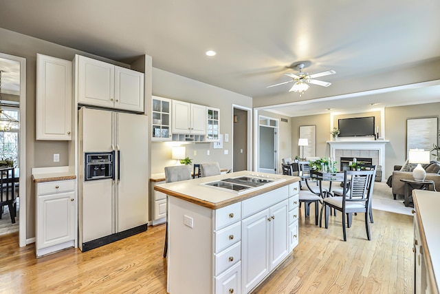 kitchen featuring white fridge with ice dispenser, white cabinets, black electric cooktop, and a fireplace