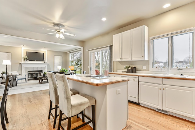 kitchen with a kitchen breakfast bar, sink, white dishwasher, and white cabinets