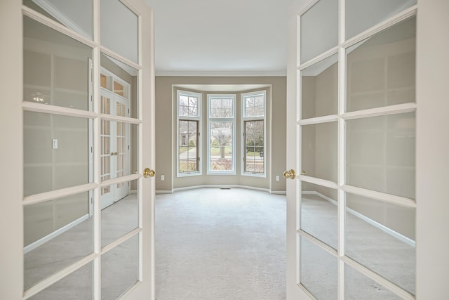 carpeted spare room featuring ornamental molding and french doors