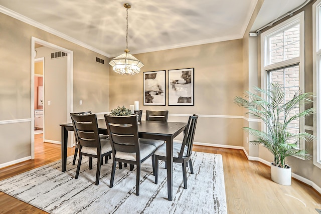 dining space featuring crown molding, hardwood / wood-style floors, and a notable chandelier