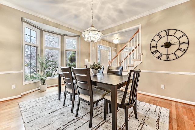 dining area with hardwood / wood-style flooring, crown molding, and a notable chandelier