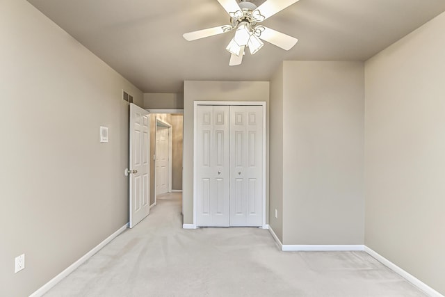 unfurnished bedroom with light colored carpet, ceiling fan, and a closet