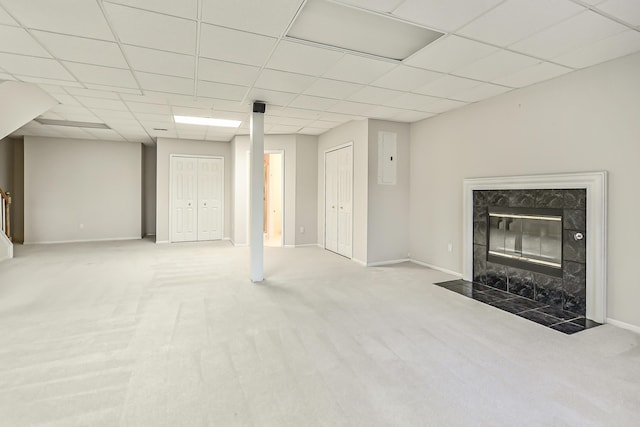 basement featuring carpet floors, a paneled ceiling, and a fireplace