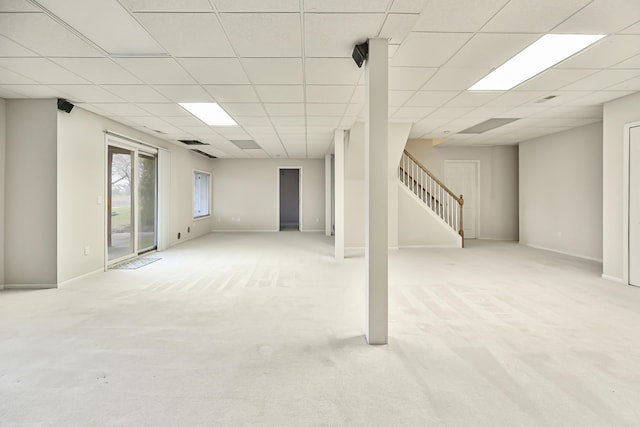 basement with a paneled ceiling and light carpet