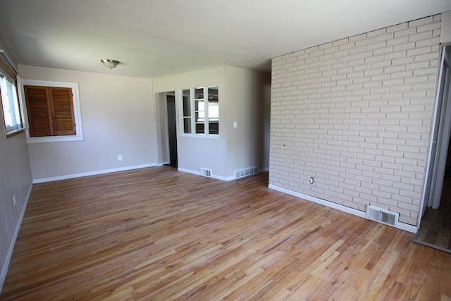 empty room featuring wood-type flooring and brick wall