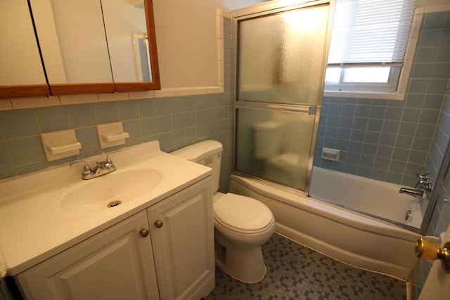 full bathroom featuring tile walls, vanity, bath / shower combo with glass door, and toilet