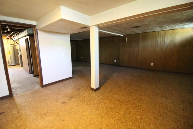 basement featuring wooden walls and water heater