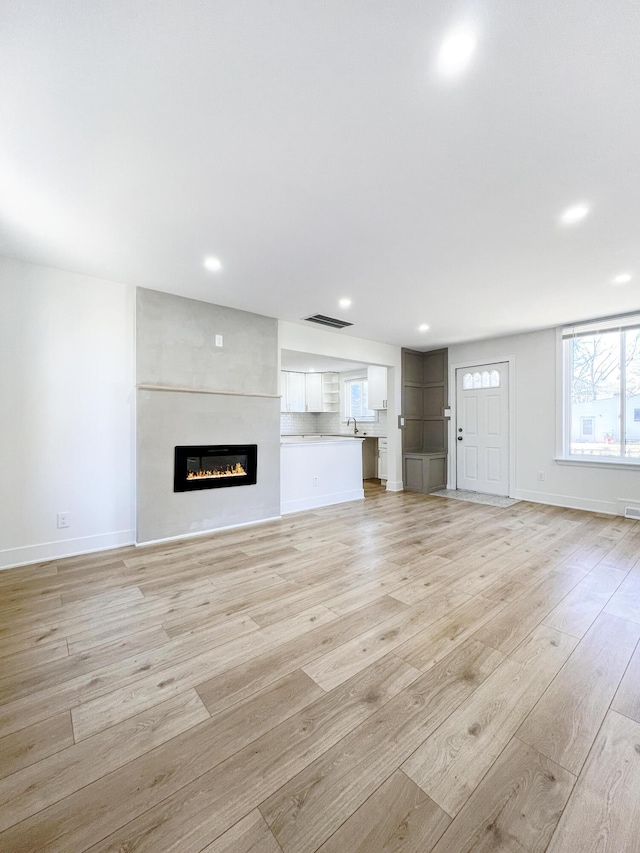 unfurnished living room featuring light hardwood / wood-style floors and a large fireplace