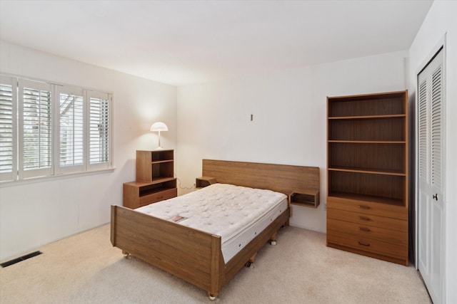 bedroom featuring light colored carpet and a closet