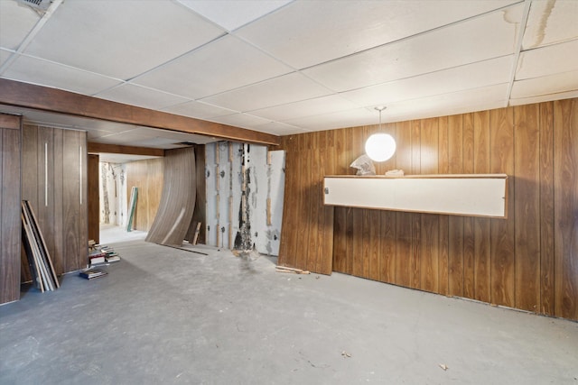 basement featuring a paneled ceiling and wooden walls