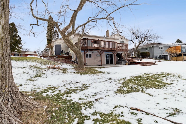 snow covered back of property featuring a deck and a chimney