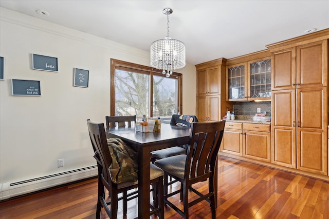 dining room with an inviting chandelier, wood-type flooring, a baseboard heating unit, and crown molding