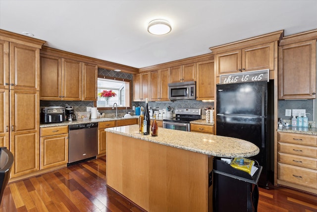 kitchen featuring decorative backsplash, appliances with stainless steel finishes, brown cabinetry, dark wood-type flooring, and a kitchen island