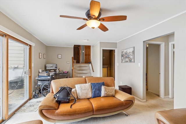 living room featuring crown molding, light colored carpet, a ceiling fan, baseboards, and stairs