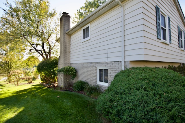 view of home's exterior with a chimney and a lawn